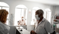People in masks at desk of clinic. Photo: FGTrade/Getty Images
