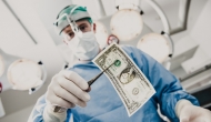 Person in PPE holding dollar bill with forceps