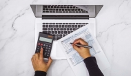 Hands at a calculator and laptop with tax form