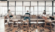Open office with workers in masks on a couch